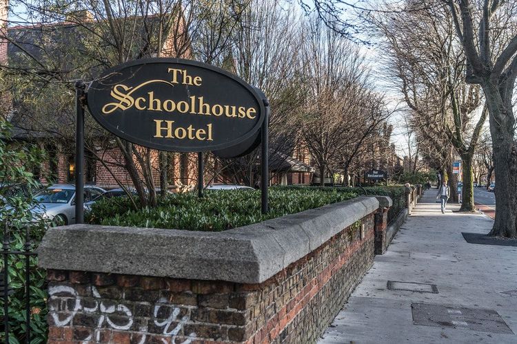The Schoolhouse Hotel sign and tree-lined boundary near Mount Street Bridge in Dublin